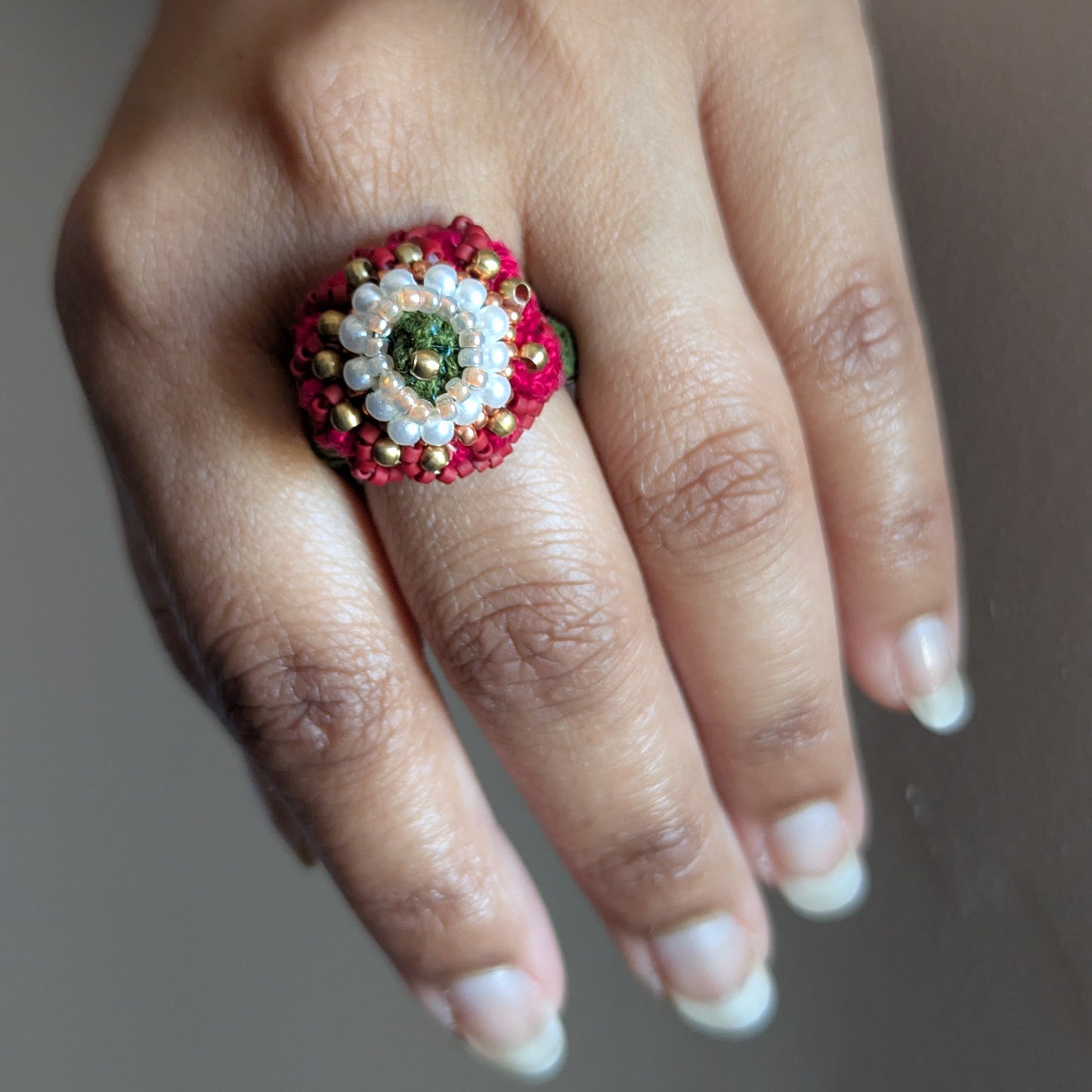 A close up of the adjustable statement red, pearl white, green and gold Shreya 5-in-1 ring element.