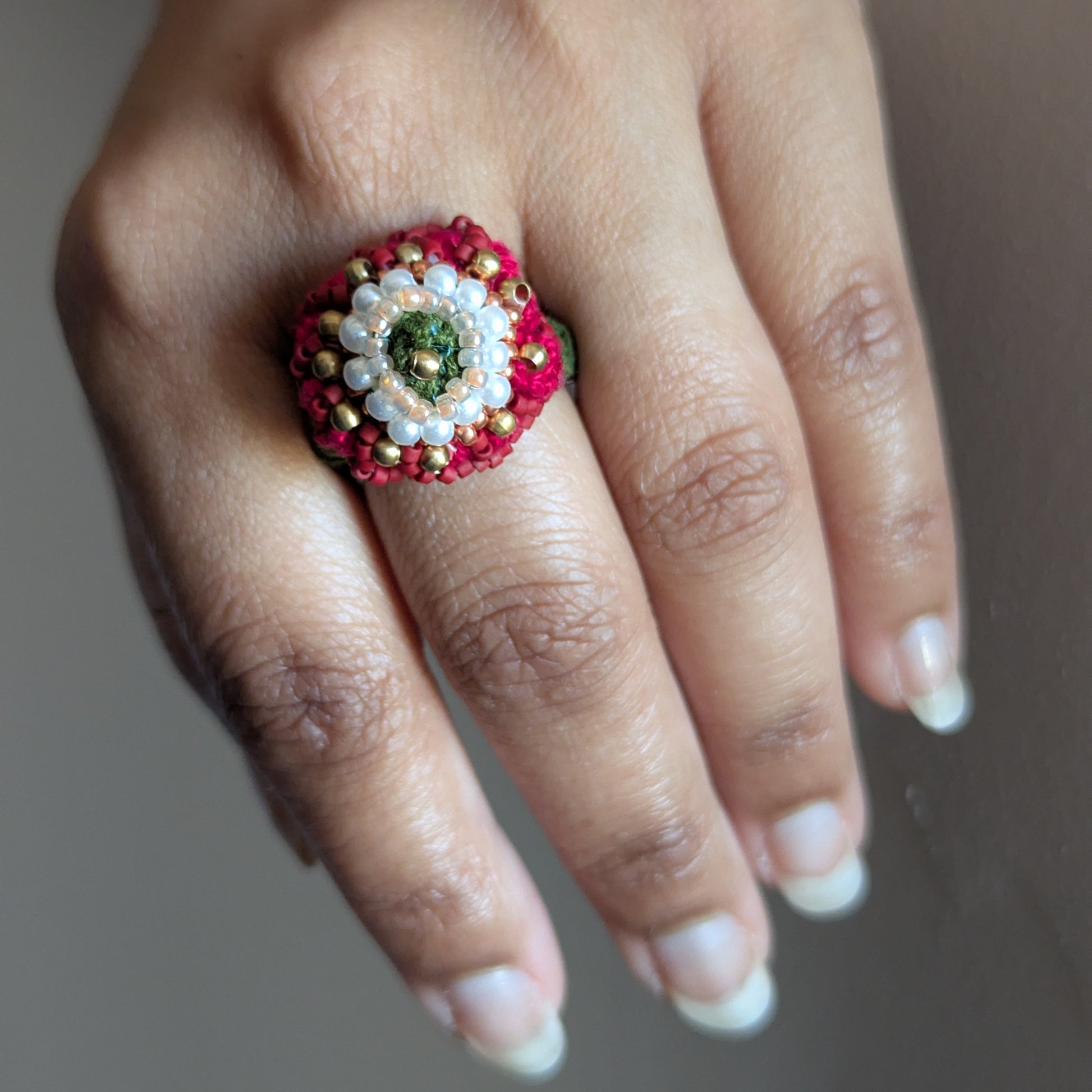 A close up of the adjustable statement red, pearl white, green and gold Shreya 5-in-1 ring element.
