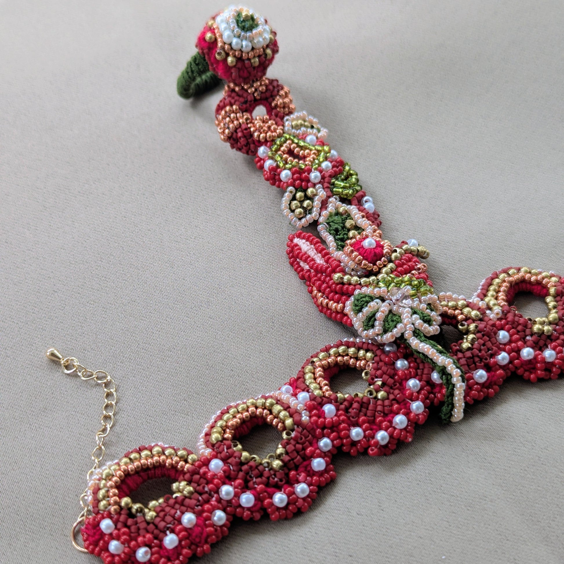 Close up detailed view of Shreya 5-in-1 red, green and gold statement beaded haath phool by sustainable Indian UK designer brand Mayaani Jewellery.