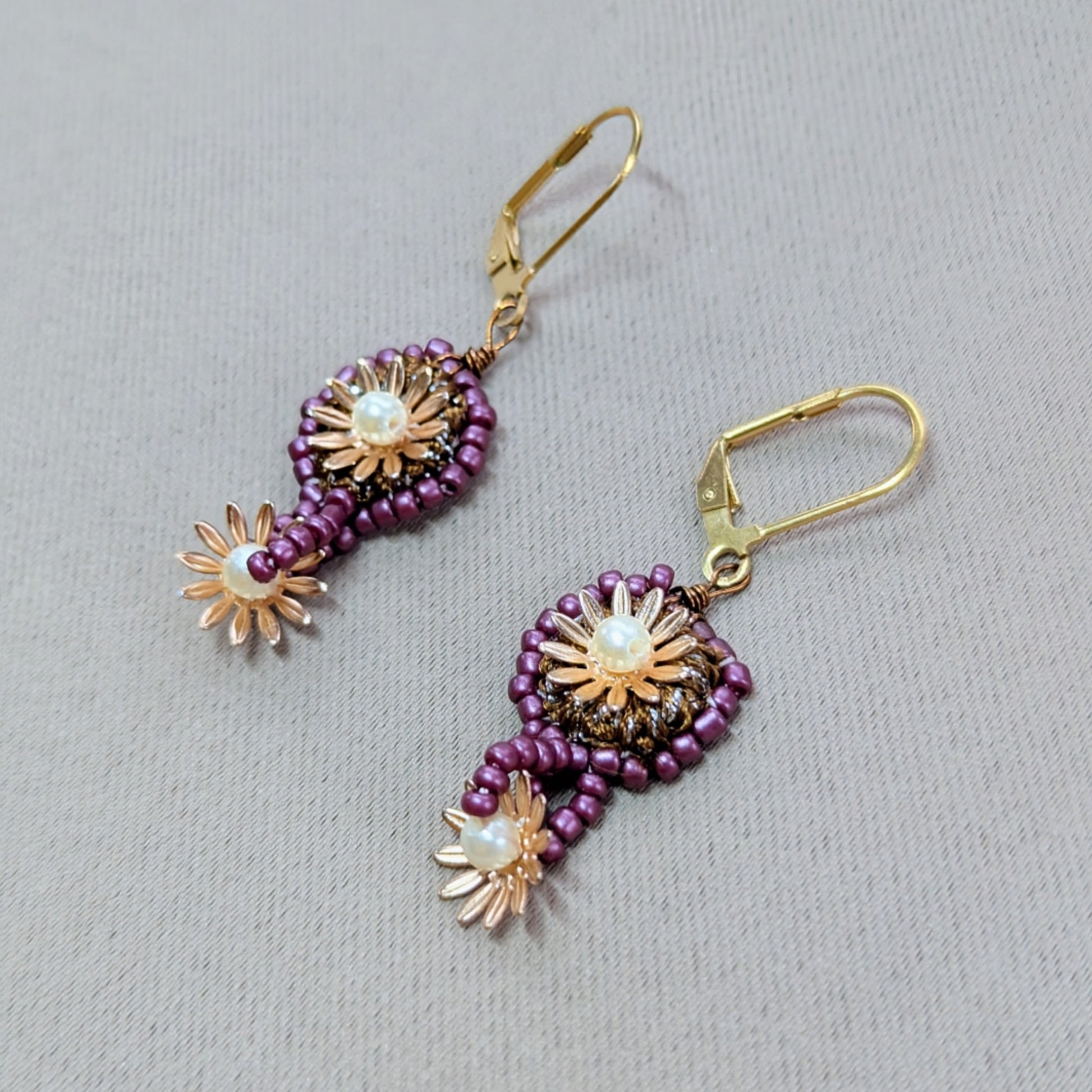 Handcrafted floral motif earrings in deep purple and bronze with gold-plated flower details by Mayaani UK.