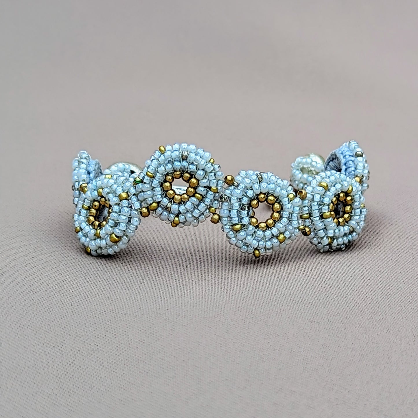 Handcrafted snowflake grey and gold winter-inspired bracelet by Mayaani Jewellery, featuring silver-plated beads and floral clasp.
