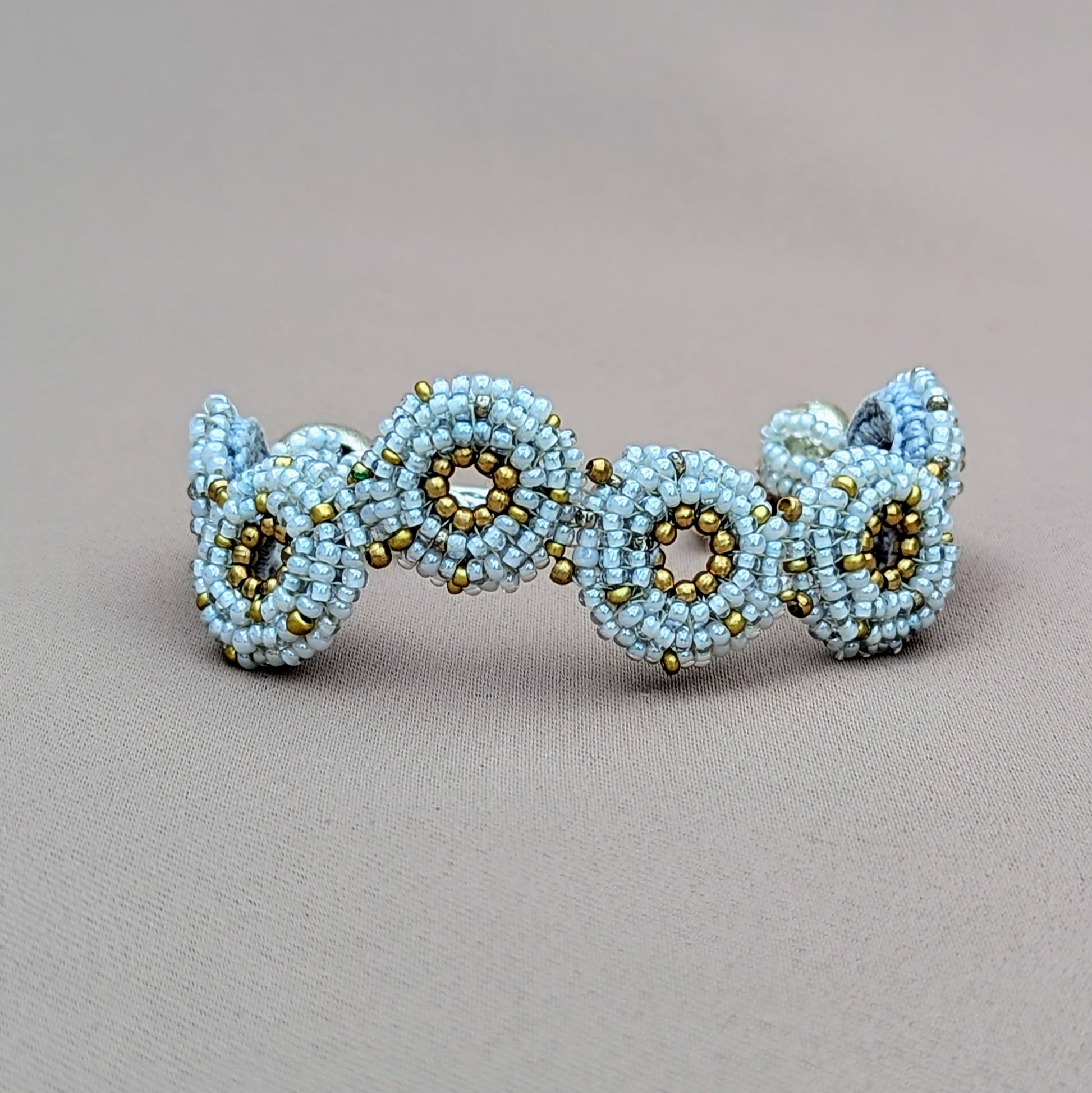 Handcrafted snowflake grey and gold winter-inspired bracelet by Mayaani Jewellery, featuring silver-plated beads and floral clasp.