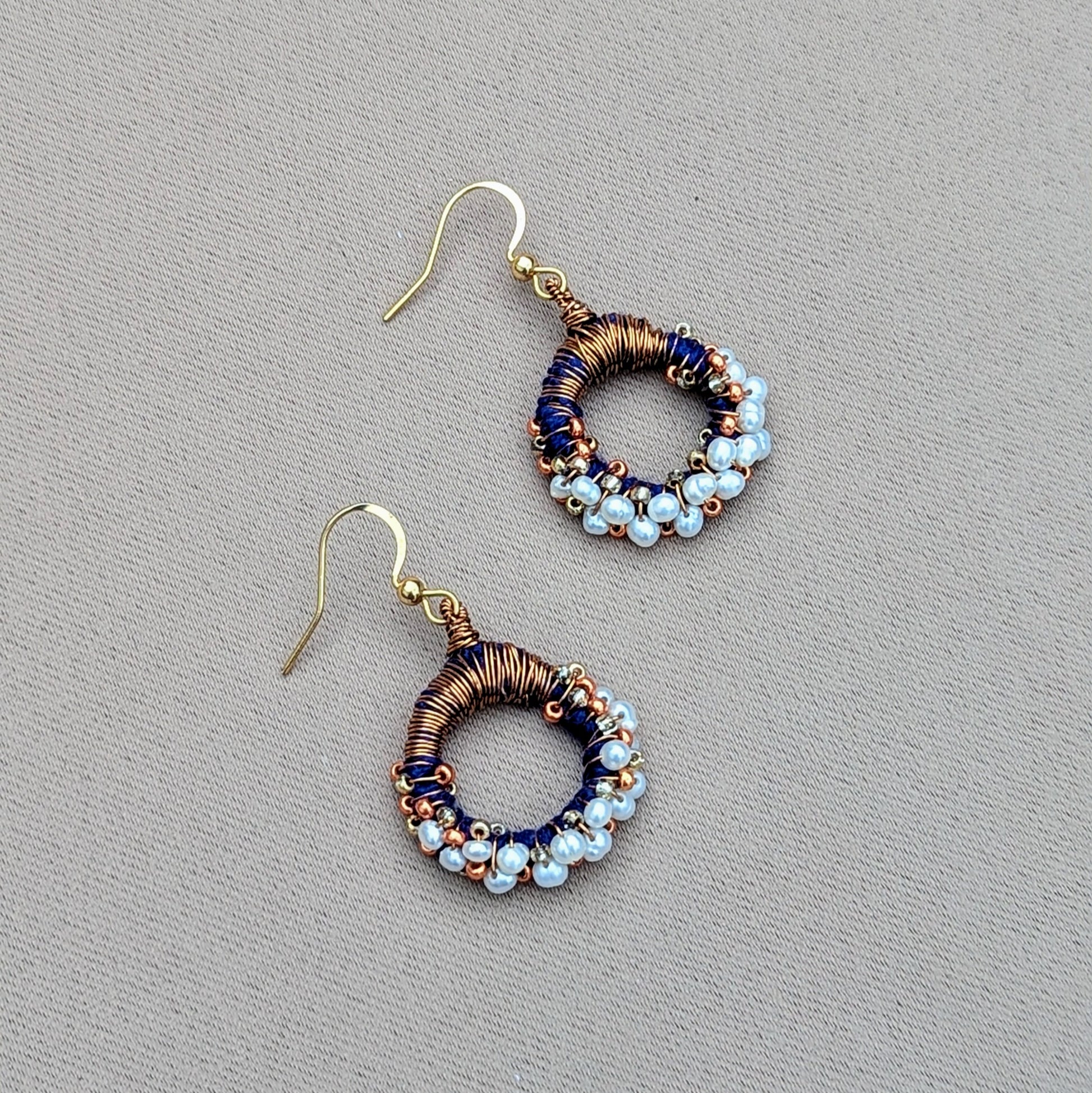 Unique pearl and copper earrings with a circular hoop style and blue accents, designed for sustainable luxury.