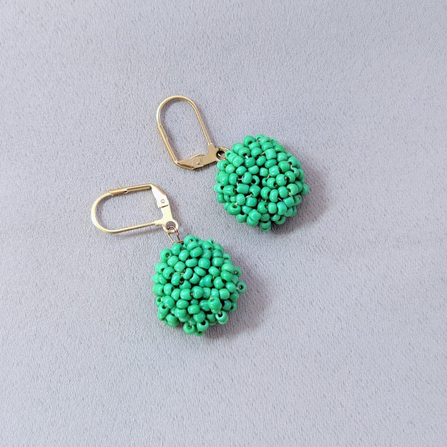 Detailed view of handcrafted green earrings revealing sustainable materials and artistic composition.