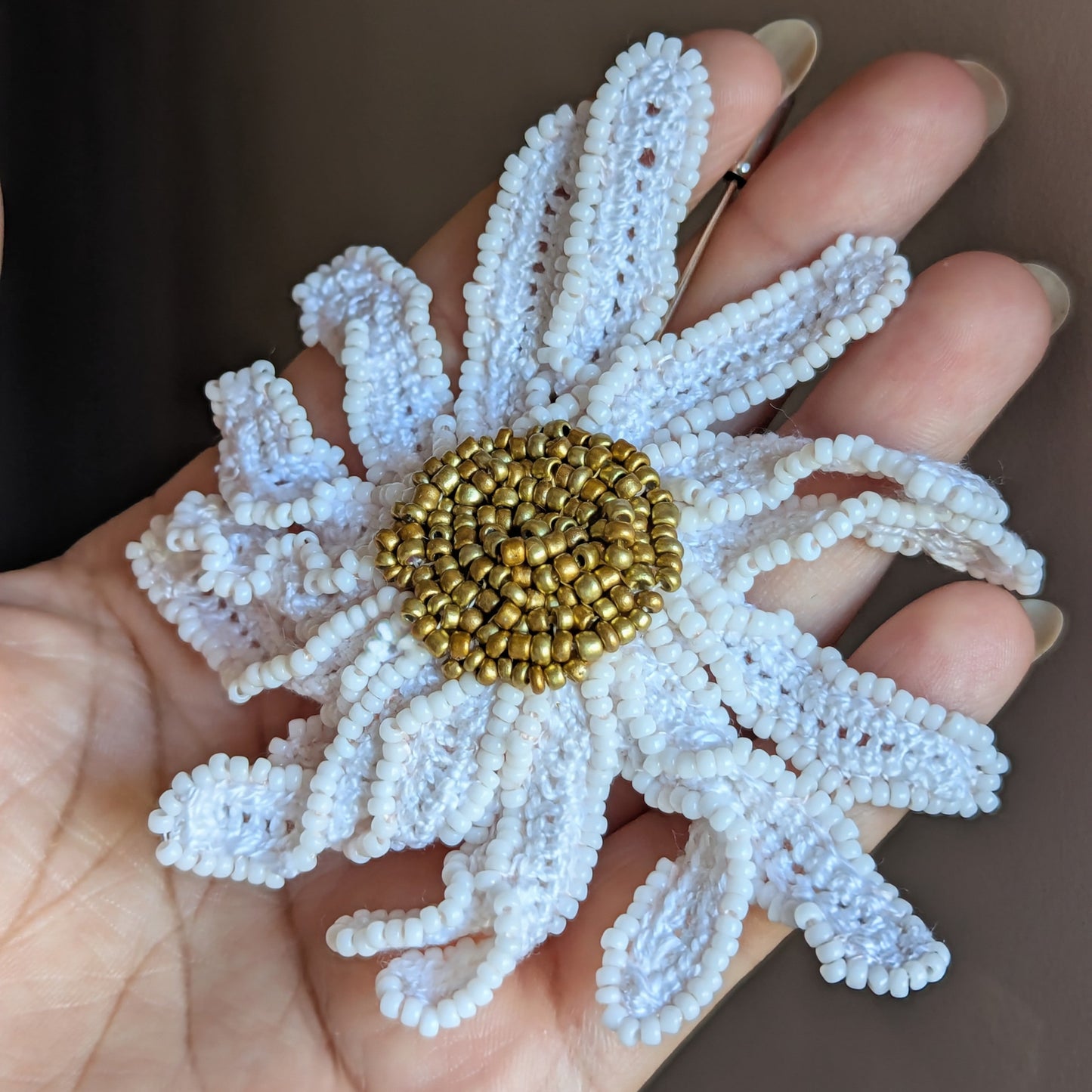 Side angle view of a botanical inspired daisy flower brooch pin crafted using hand crochet and hand bead embroidery techniques.