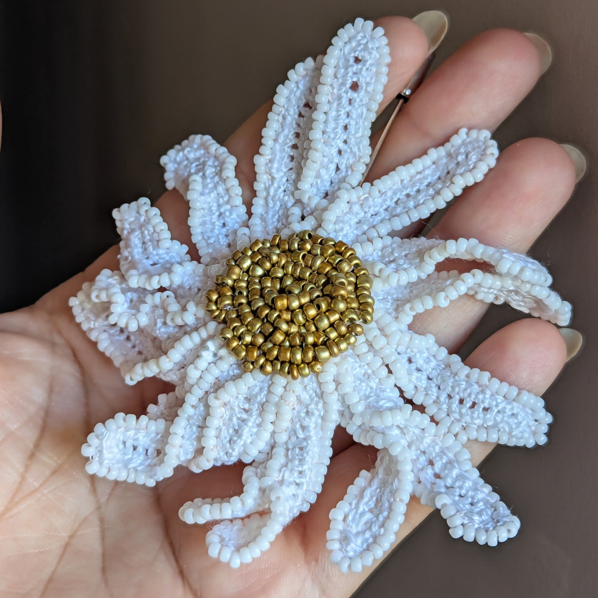Side angle view of a botanical inspired daisy flower brooch pin crafted using hand crochet and hand bead embroidery techniques.