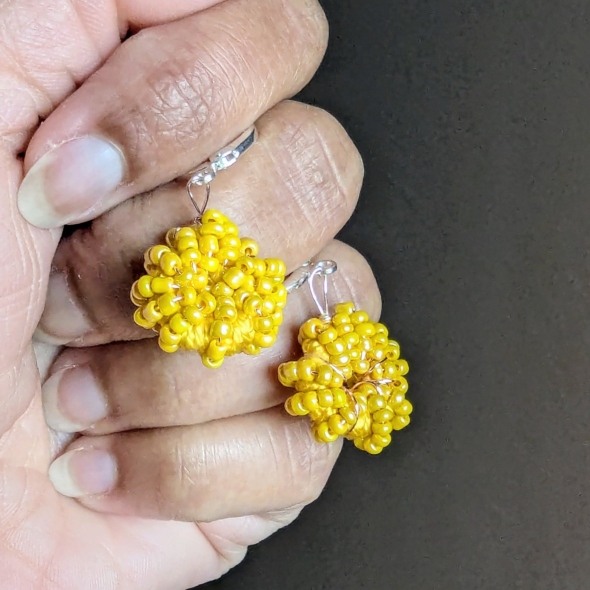 Hand modelling Raiya yellow beaded hoop earrings handcrafted in bright sunflower yellow tones and expertly finished with 925 Sterling silver clasps.