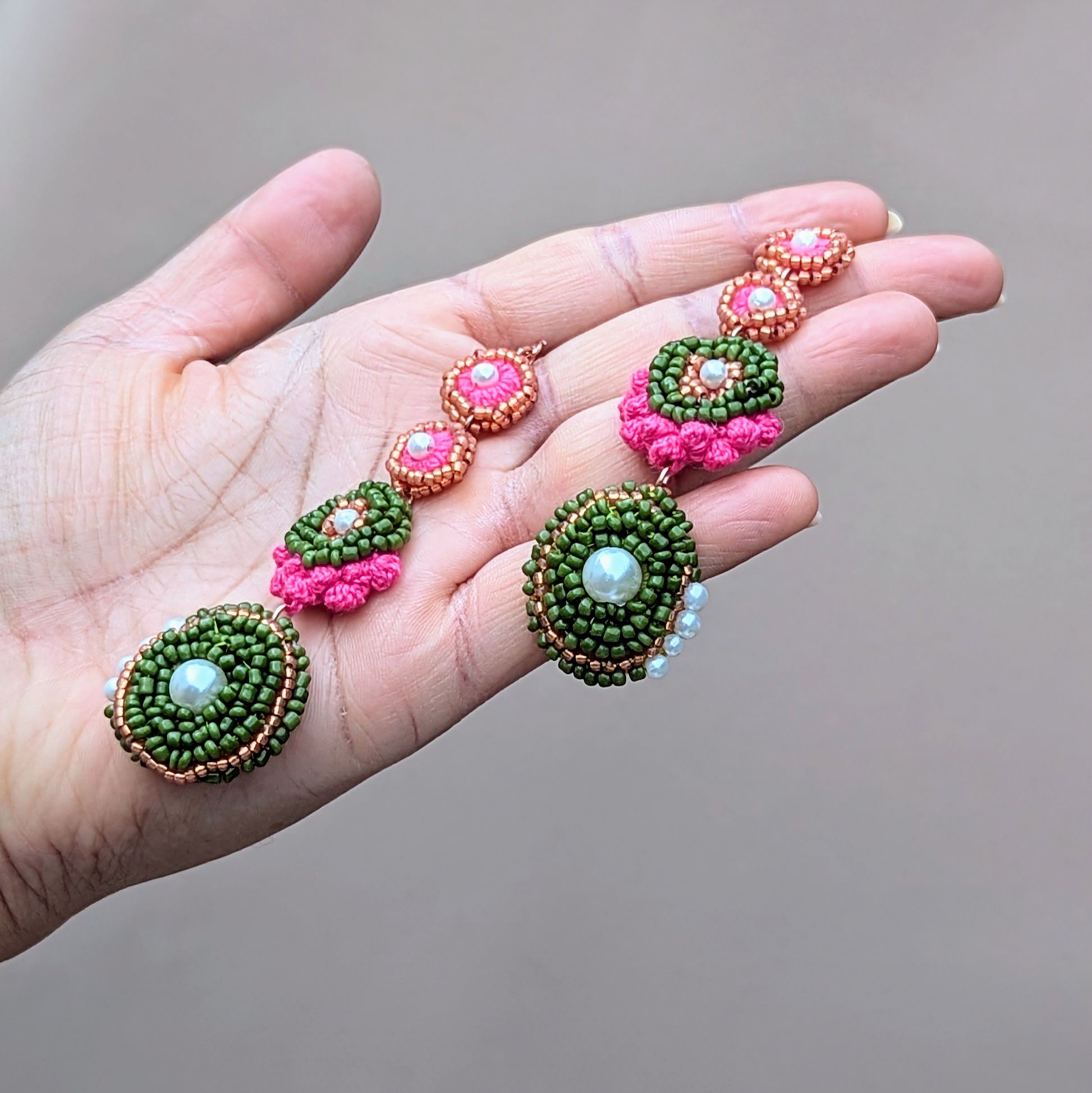 Side profile of Minna statement earrings held in hand, showcasing dimensional beadwork, crocheted structure, and elegant drop length.