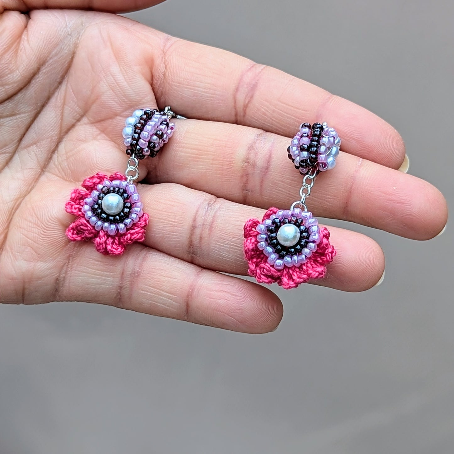 Hand holding a pair of purple, pink and white Indian scrap bead earrings with eco-conscious craftsmanship.