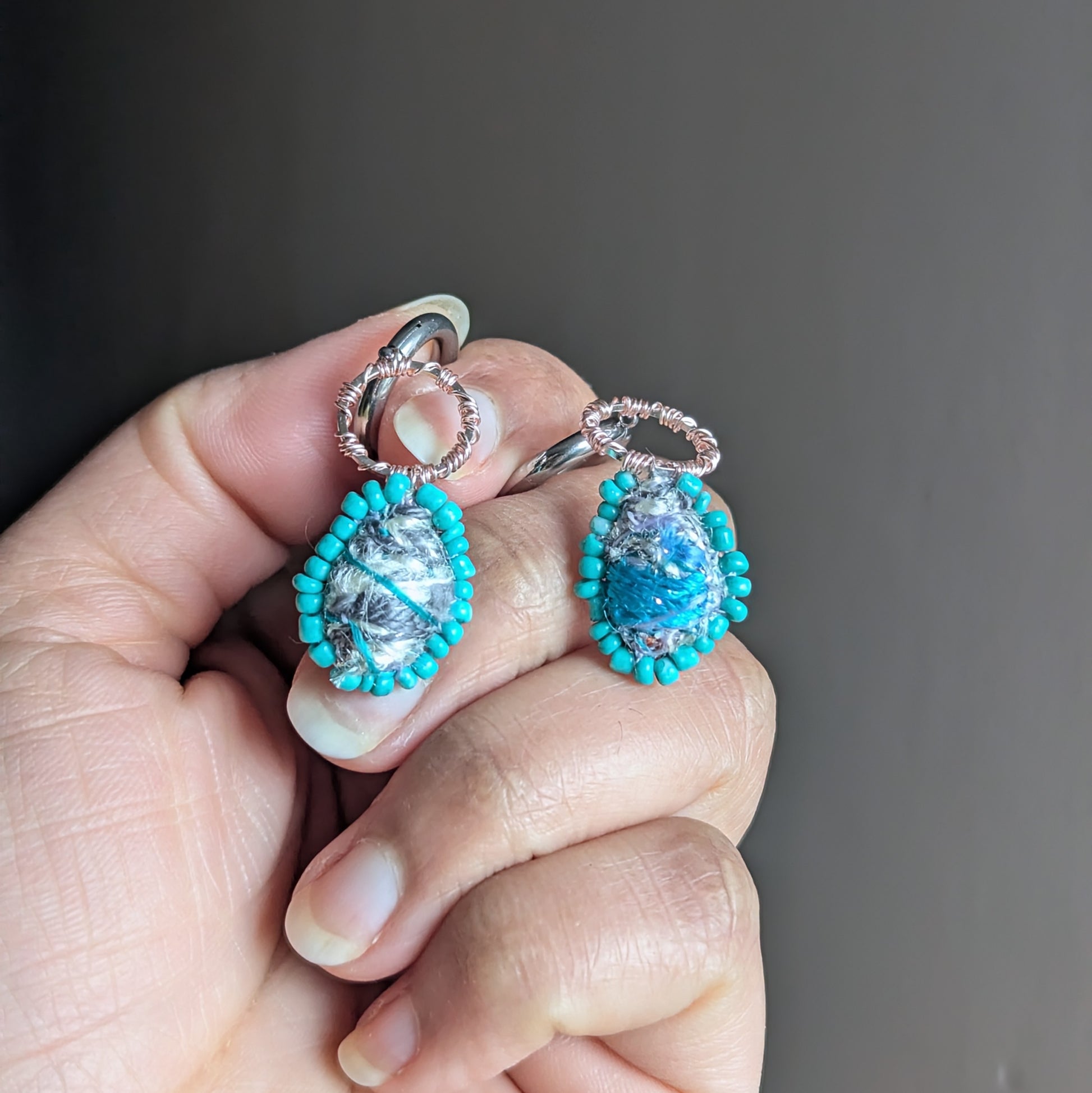 Tarini asymmetric scrap bead earrings with turquoise glass seed bead border held in hand, handmade sustainable jewellery UK.