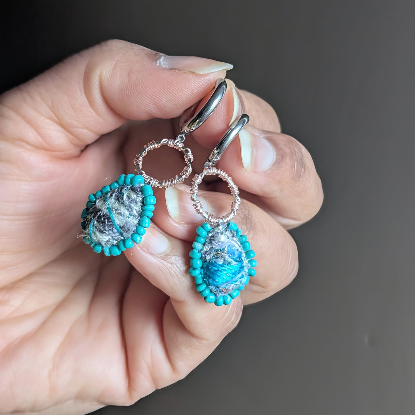 Tarini sustainable handmade earrings resting in hand with turquoise vintage seed bead frame and ocean-inspired tones.