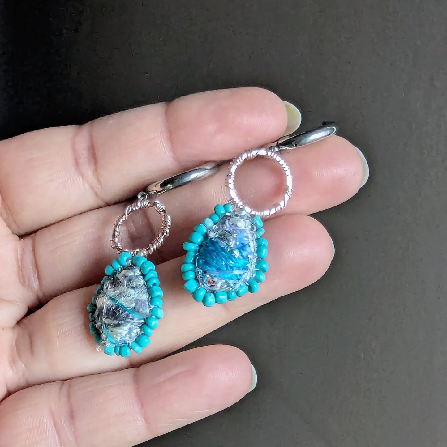 One-of-a-kind Tarini sustainable earrings held in hand featuring textile heirloom fragments and stainless steel hoop fittings.