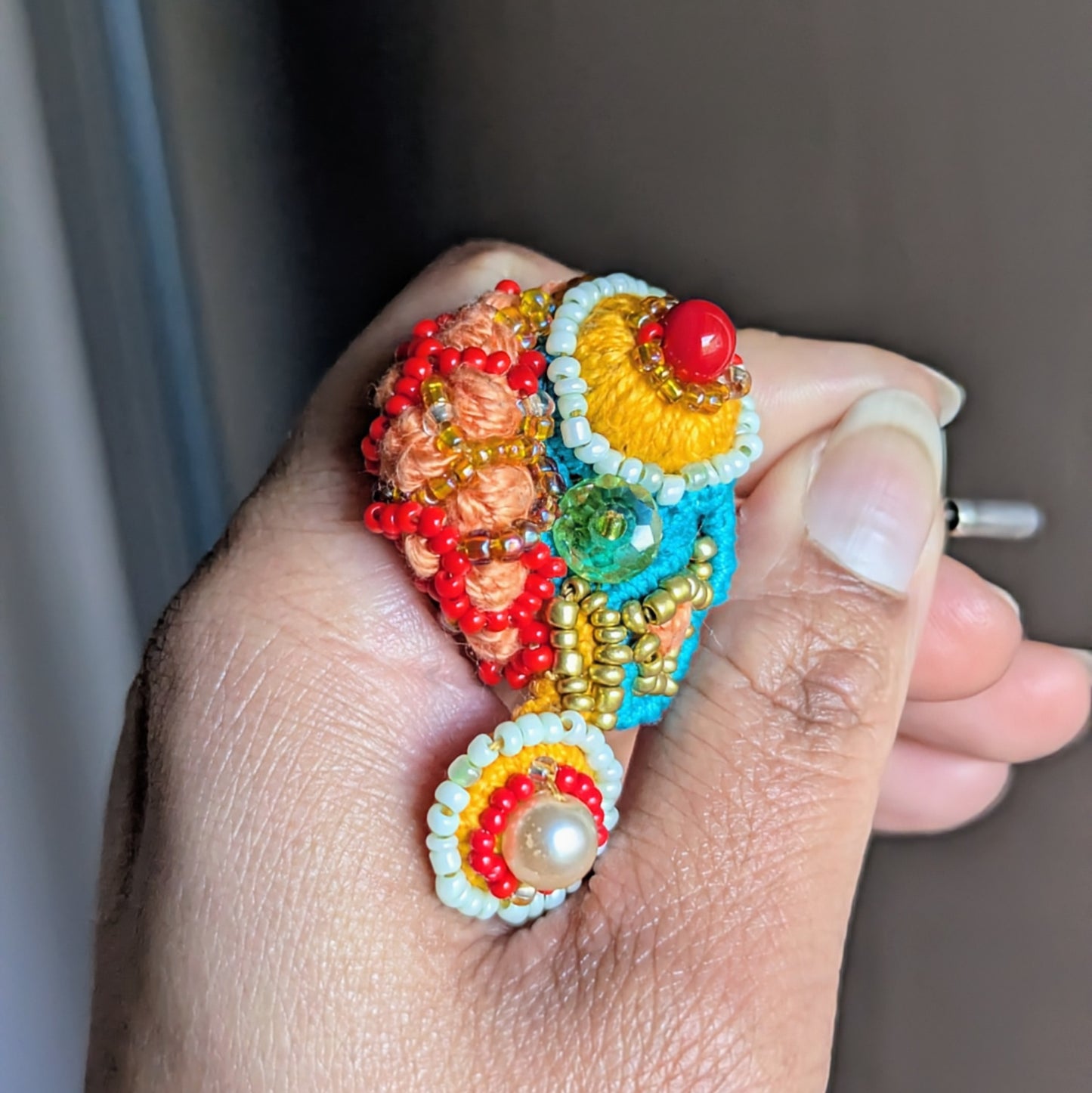 Angled view of Tejasi handmade statement brooch highlighting yellow sunburst bead centre, vintage green crystal and sculptural layered beadwork.