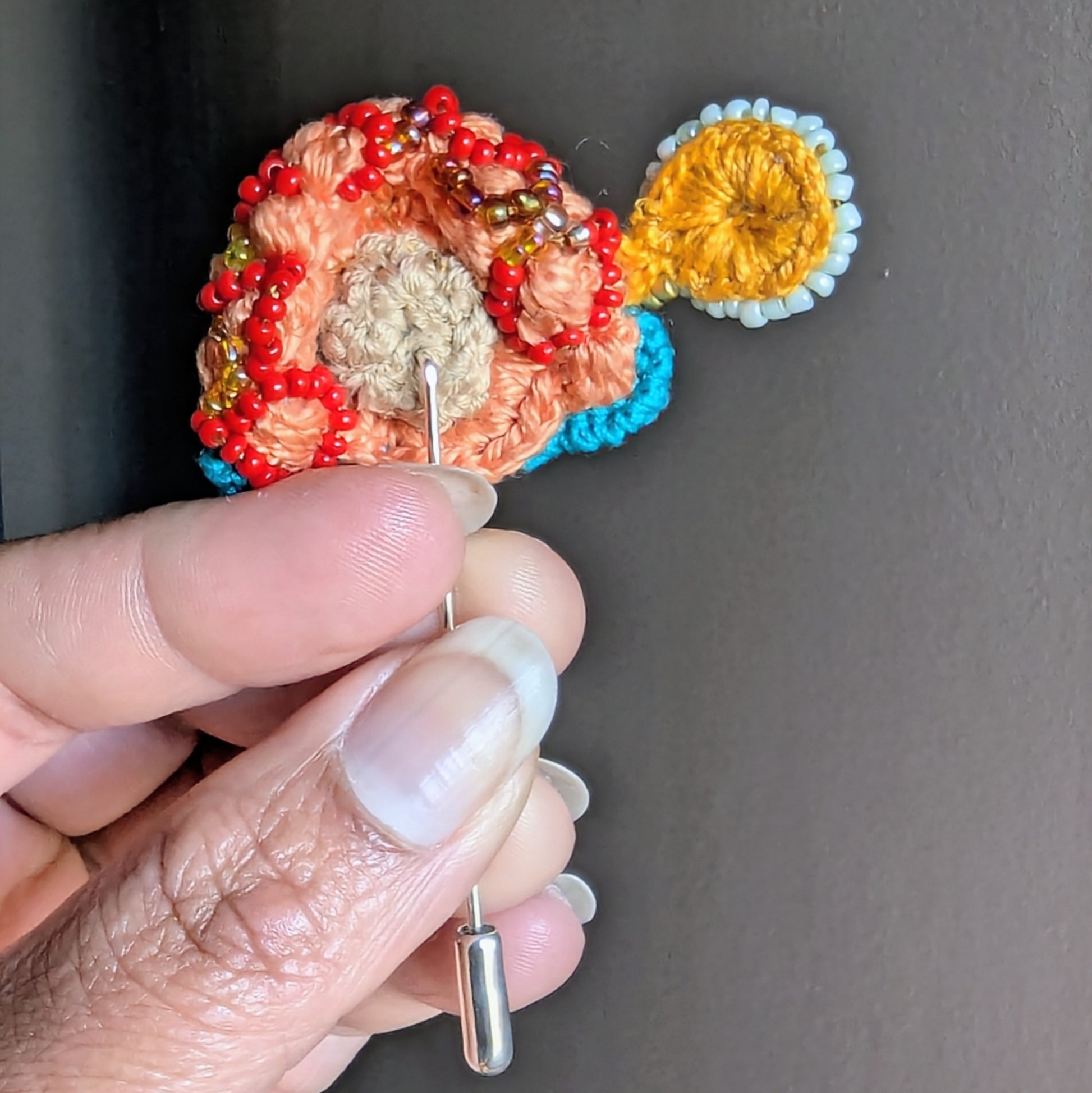 Back view of Tejasi artisan brooch showing stainless steel pin fastening and structured textile bead embroidery construction.