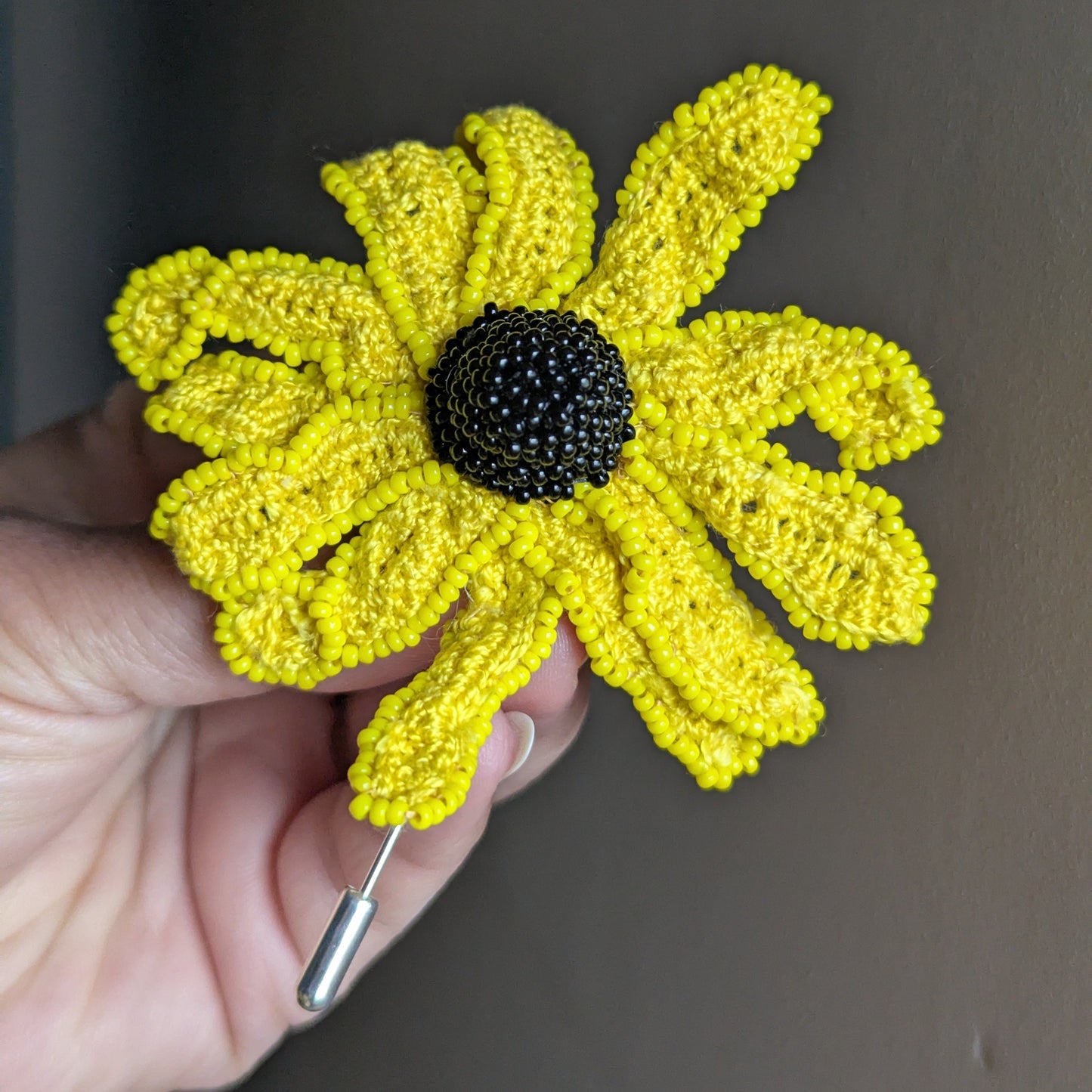 Vamika brooch close up - dramatic black seed bead centre against vivid yellow petals.