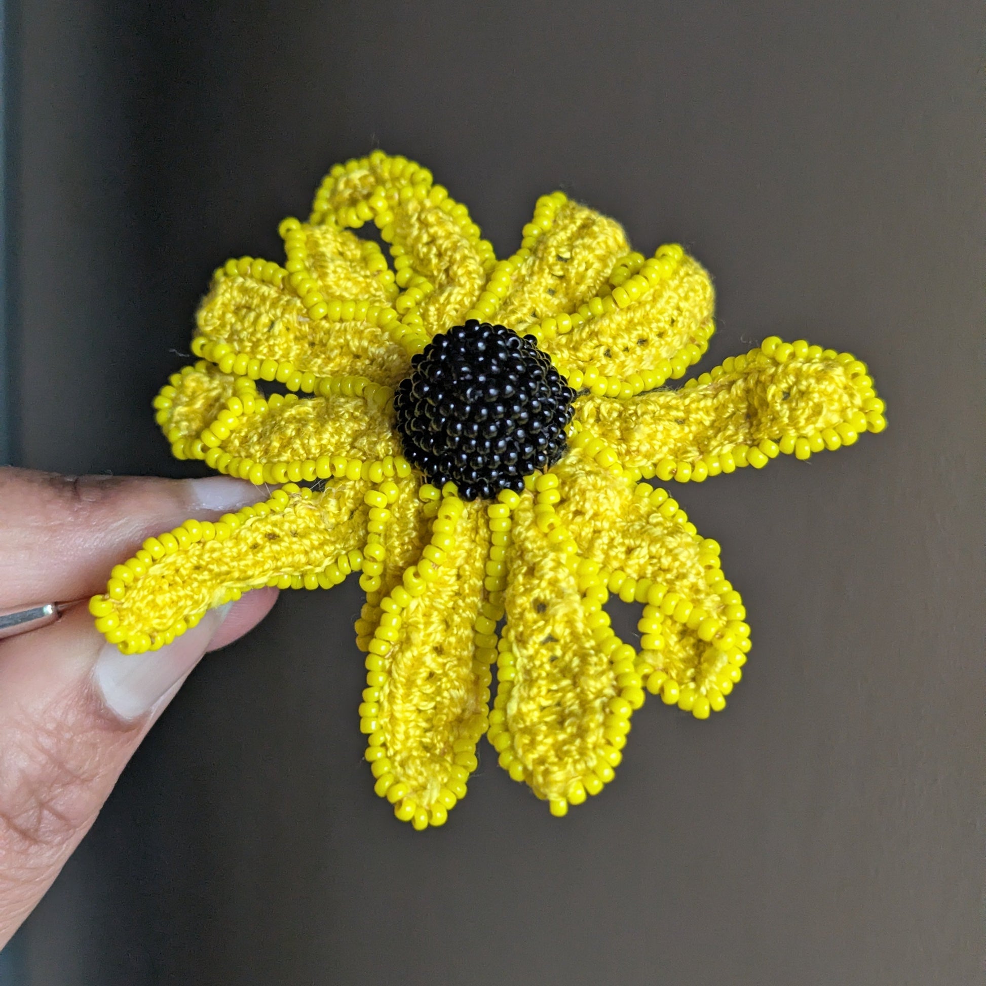 Vamika Garden of Becoming rudbeckia brooch pin in hand - handmade in yellow and black by Mayaani Jewellery UK.