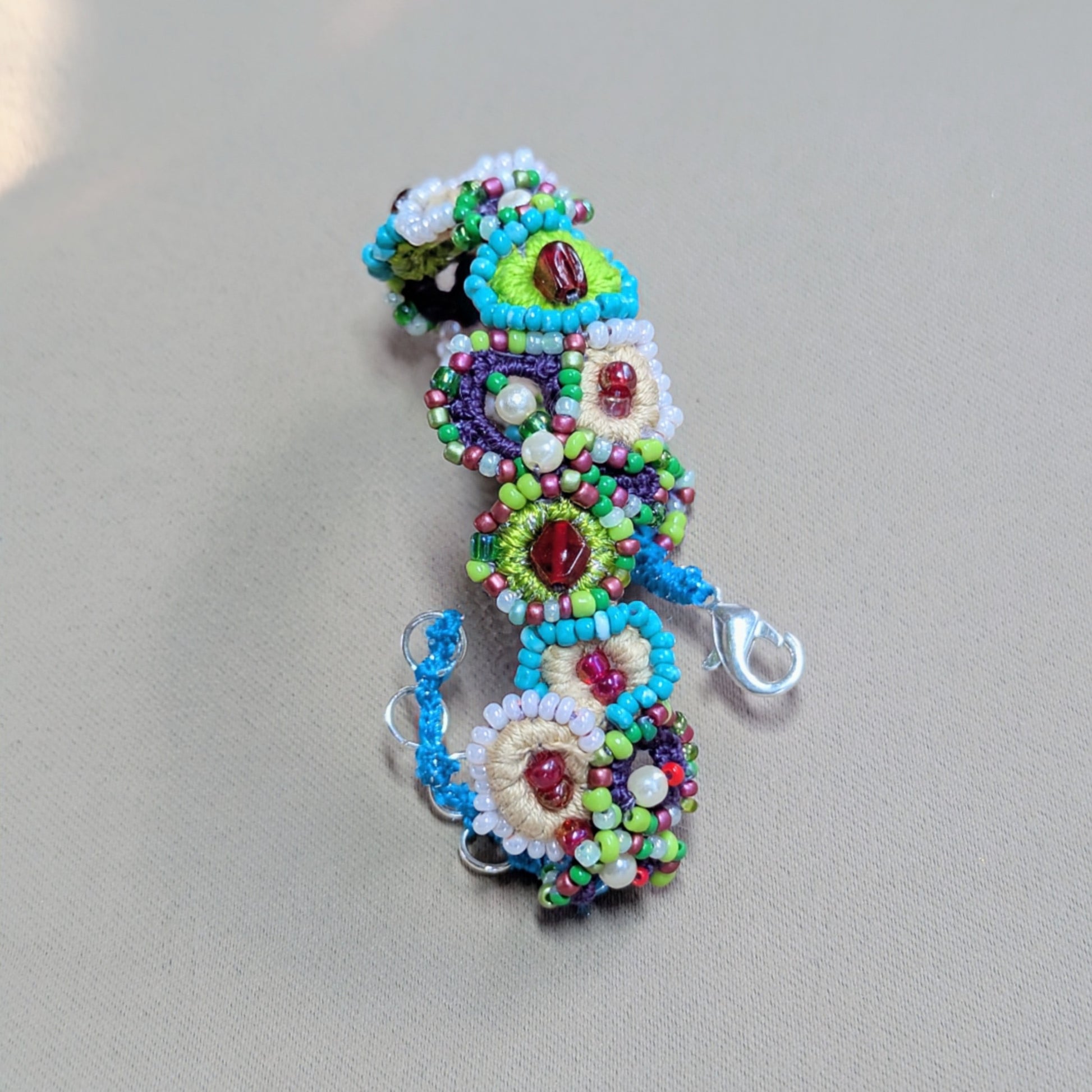 Close-up of a handmade beaded bracelet revealing intricate crochet work, Czech glass seed beads, vintage beads, and seed pearls in a vibrant garden-inspired palette.