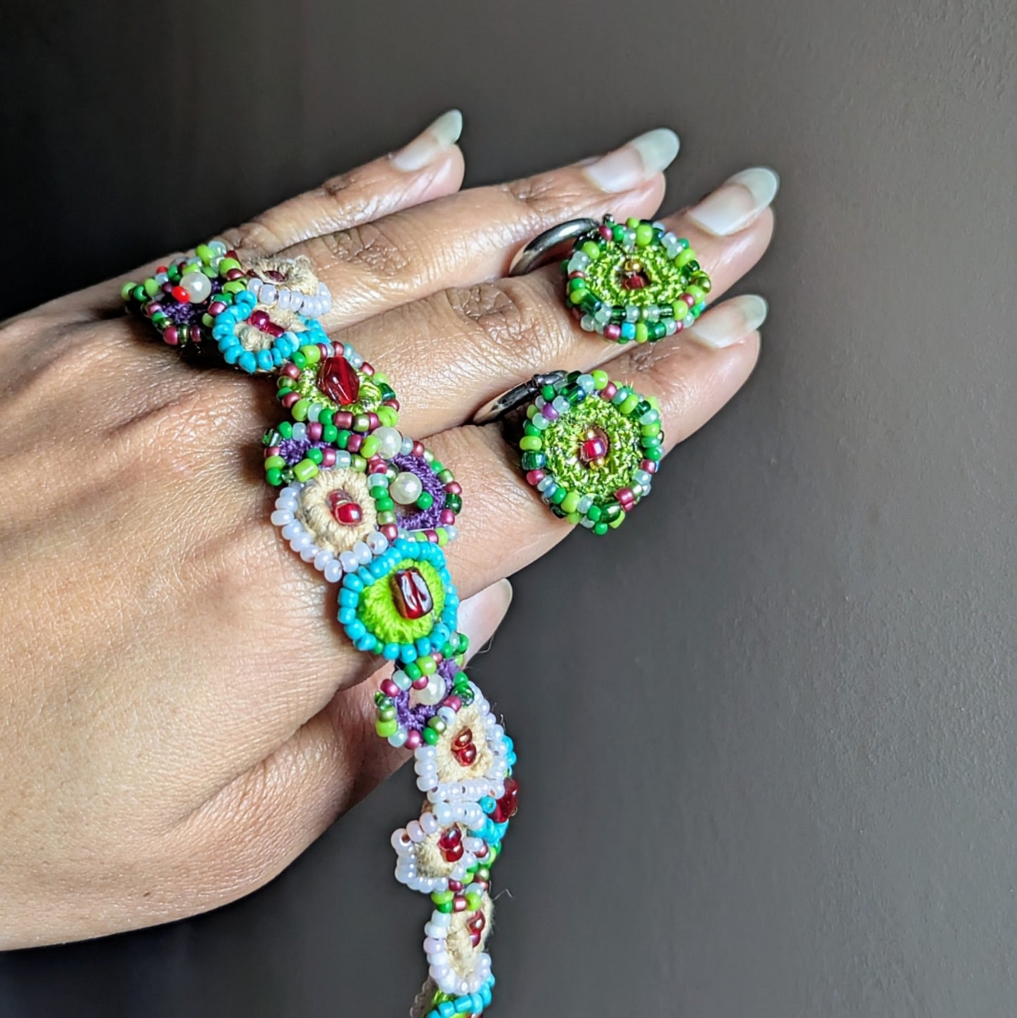 Artisan made Vana Journey garden bracelet and earrings held in hand, crafted using vintage and new glass beads and pearl cotton.