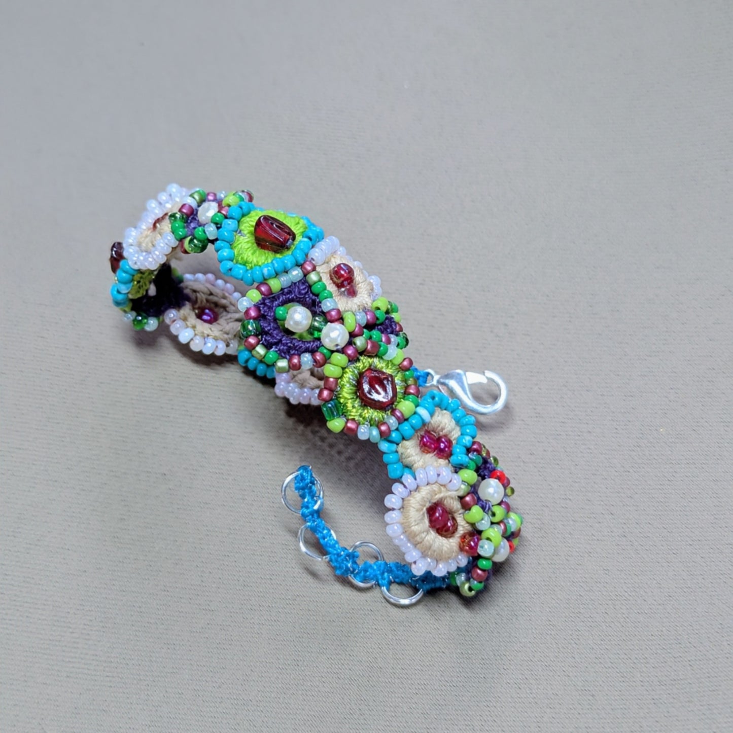 Angled flat lay of a garden-inspired beaded bracelet showing depth, layered beadwork, and the organic flow of the handcrafted design.