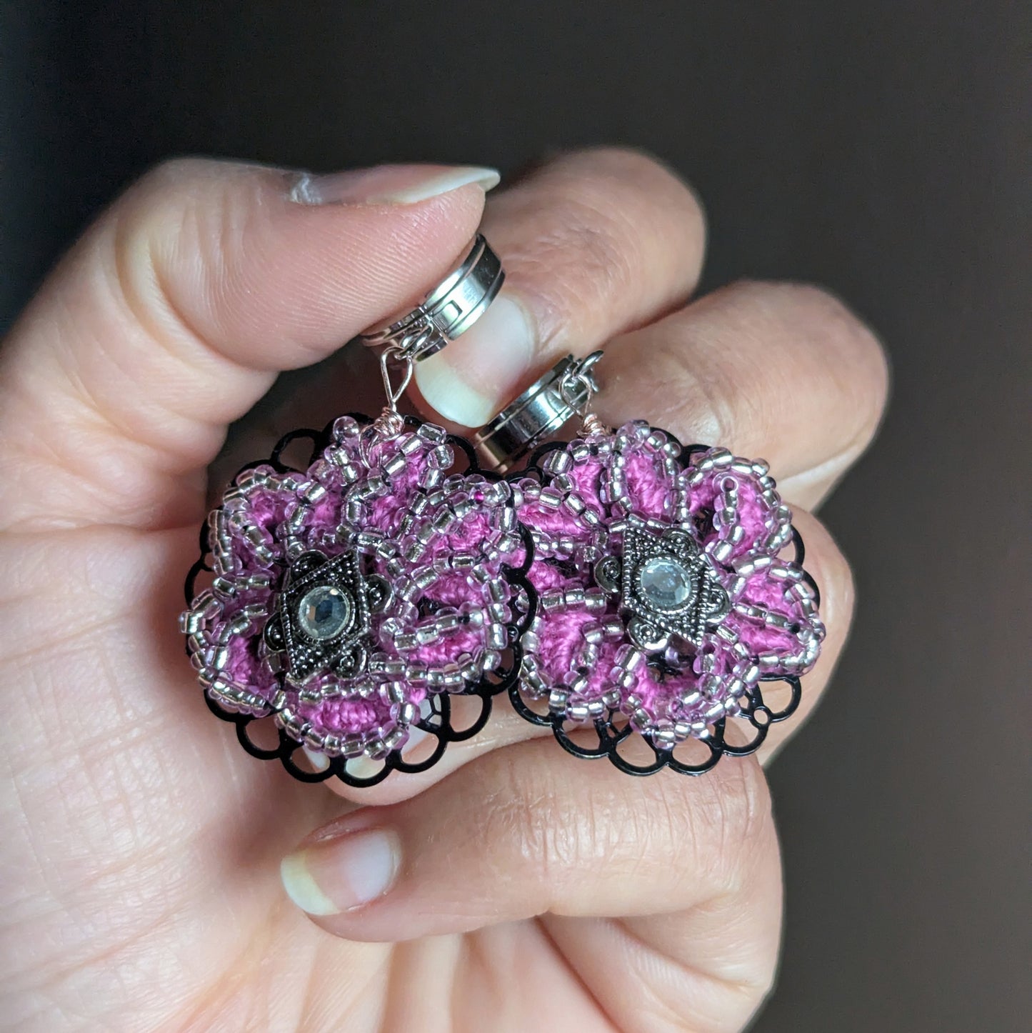 Vanya pink silver lined beaded earrings held in hand showing black filigree base and vintage crystal centre.