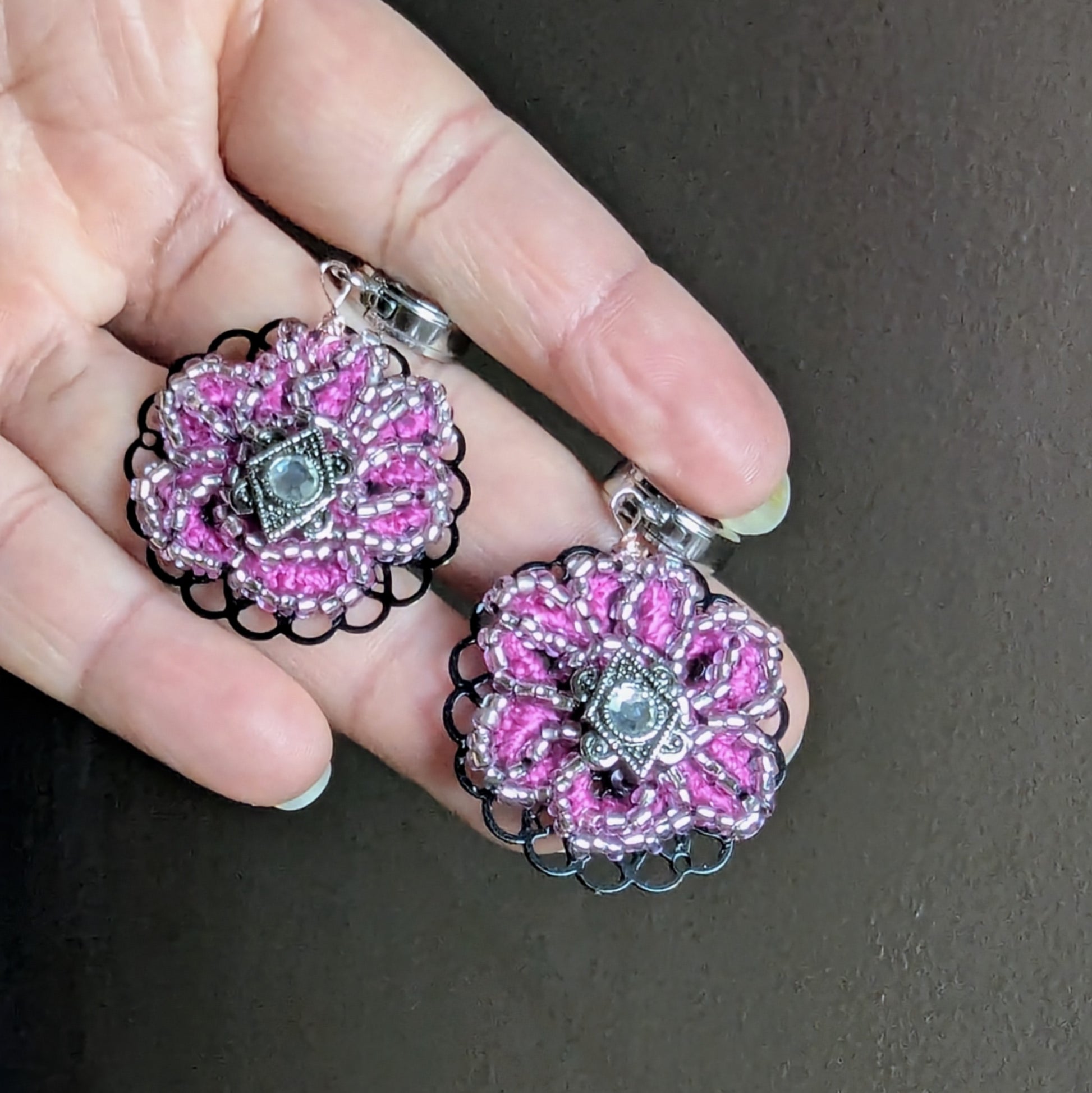 Artisan pink and silver statement earrings with vintage cubic zirconia centre held against natural light.