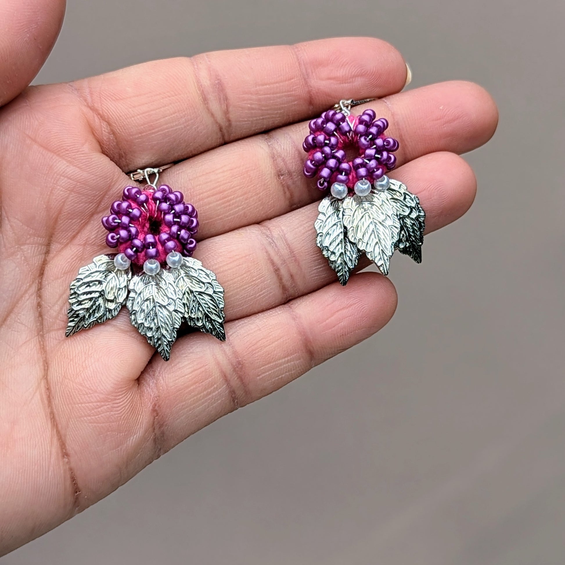 Close-up of silver-plated leaf earrings with Czech glass seed beads and vintage seed pearls.