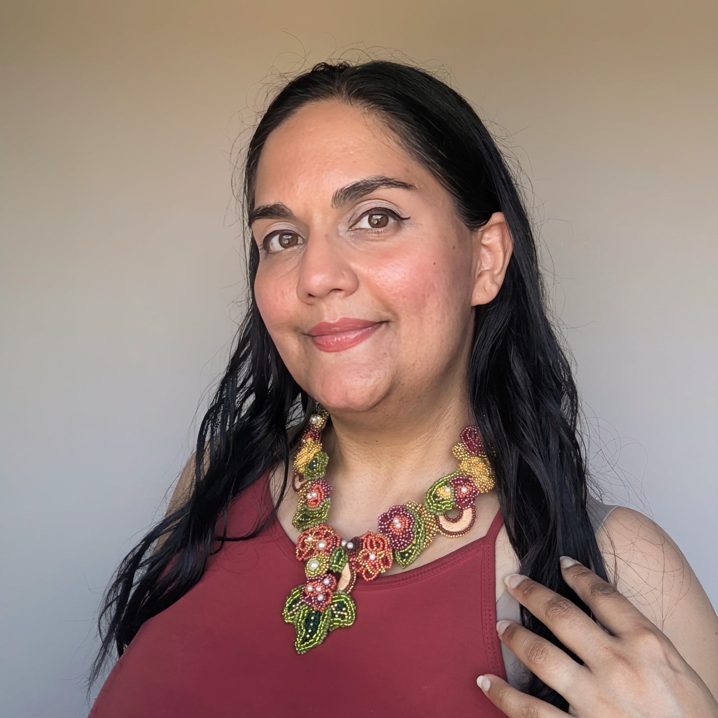 Megha founder of Mayaani Jewellery wearing the Rukmini 2-in-1 botanical statement necklace handmade in olive green, gold and burgundy with accents of yellow.